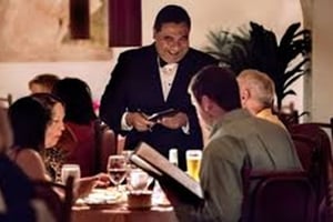 A server at a fine dining restaurant helping customers choose a wine